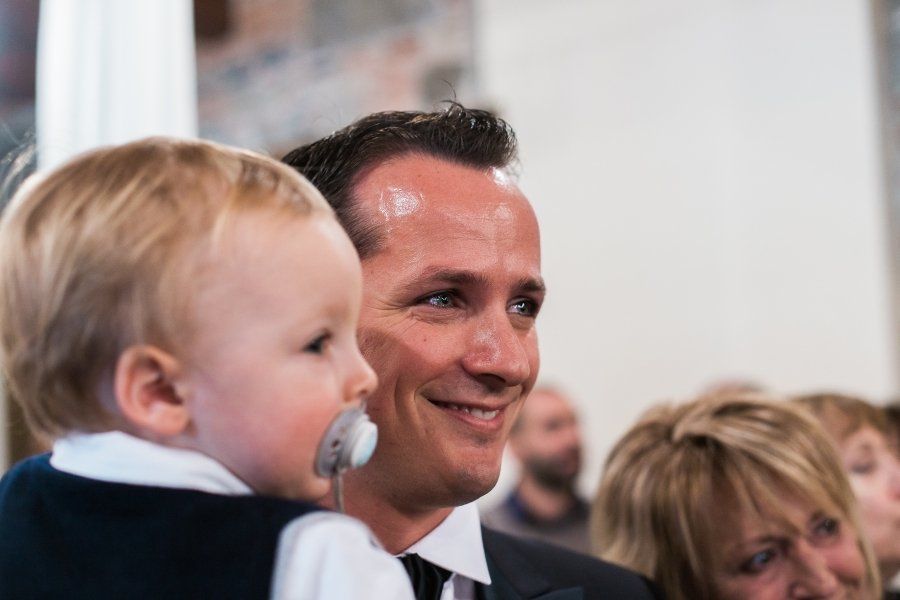A man in a suit and tie is holding a baby in his arms.