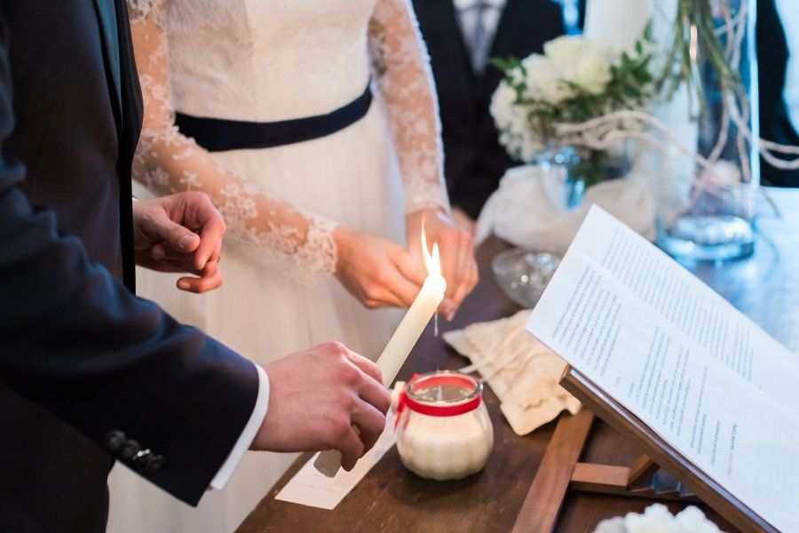 A bride and groom are lighting a candle during a wedding ceremony.