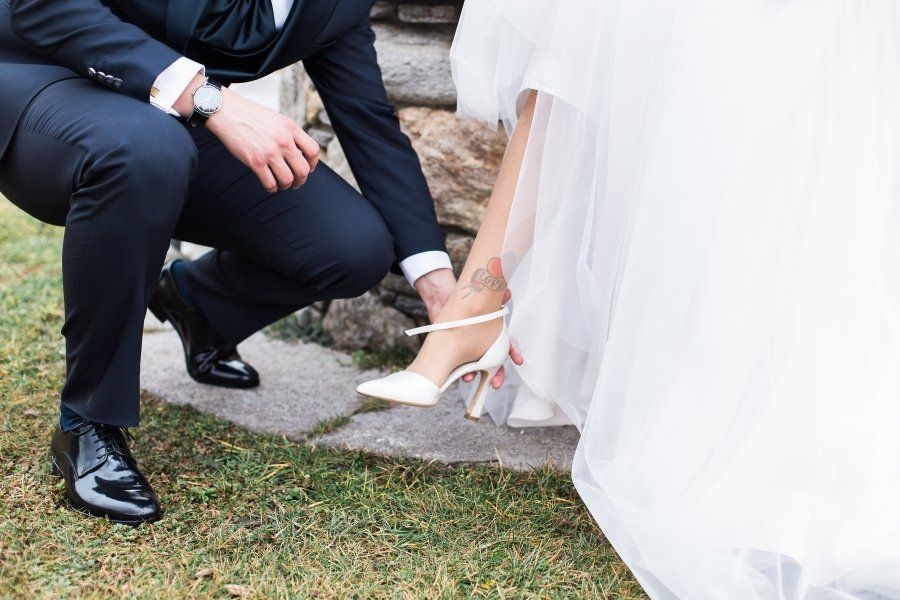 A bride and groom are tying their wedding shoes.