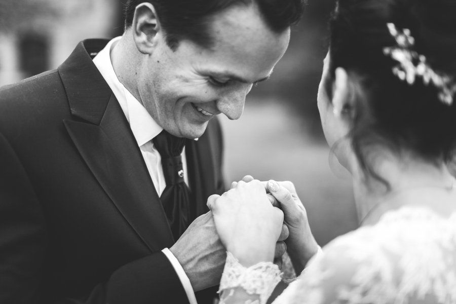 A black and white photo of a bride and groom holding hands.