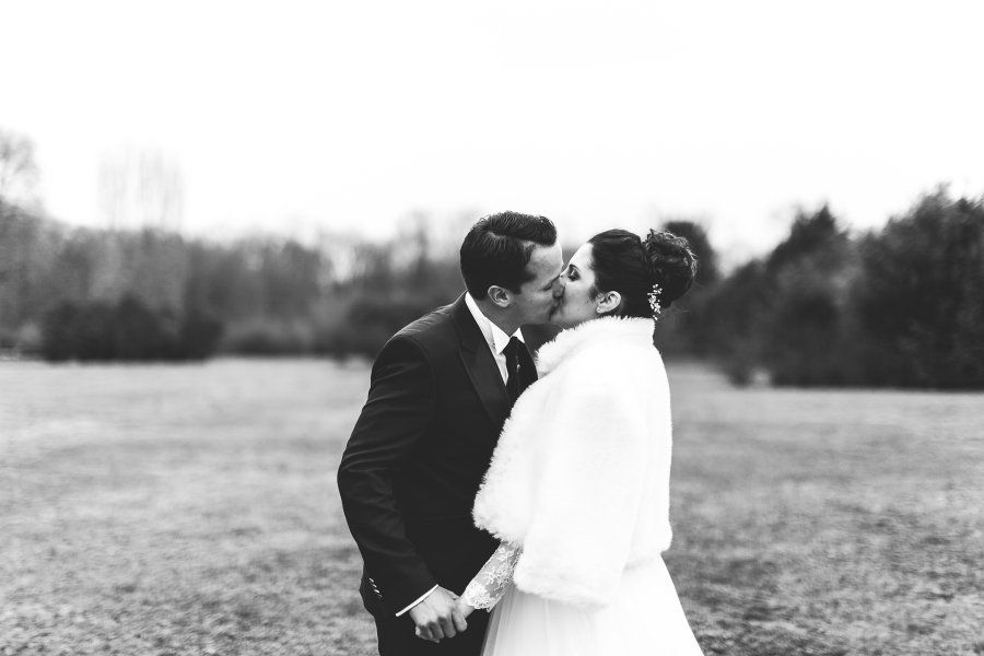 A bride and groom are kissing in a field.