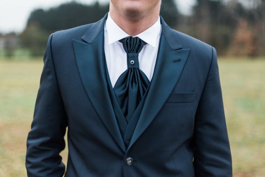 A man in a suit and tie is standing in a field.
