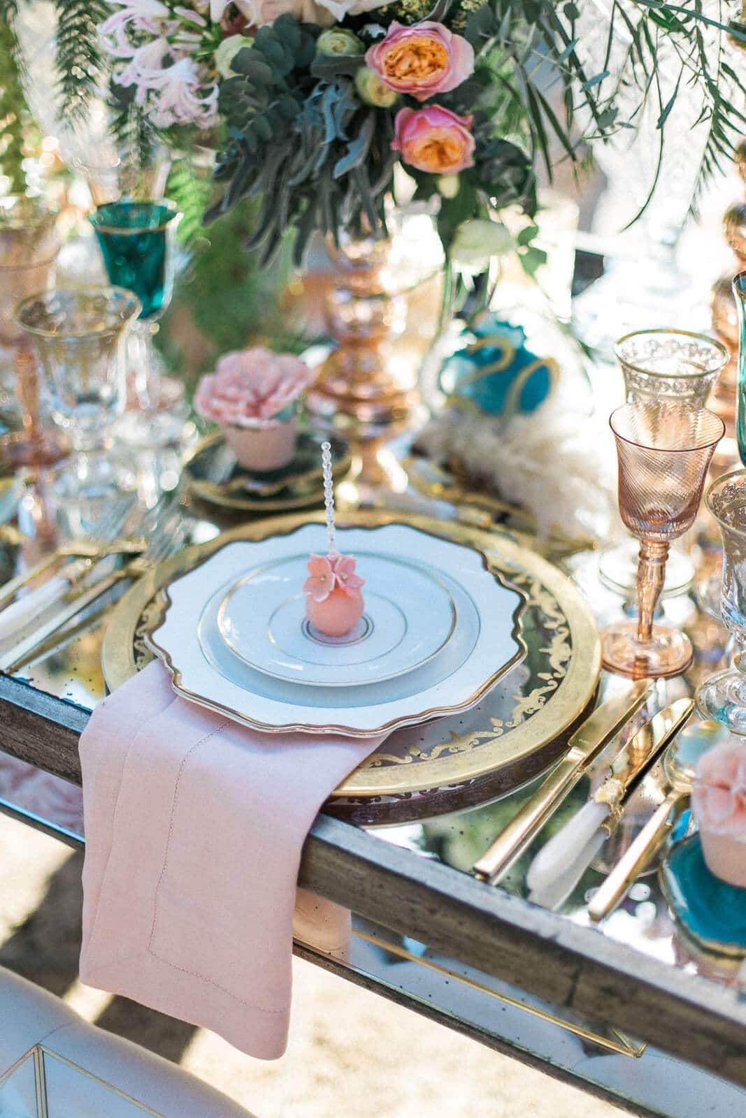 A table setting with plates , candles , glasses , and flowers.