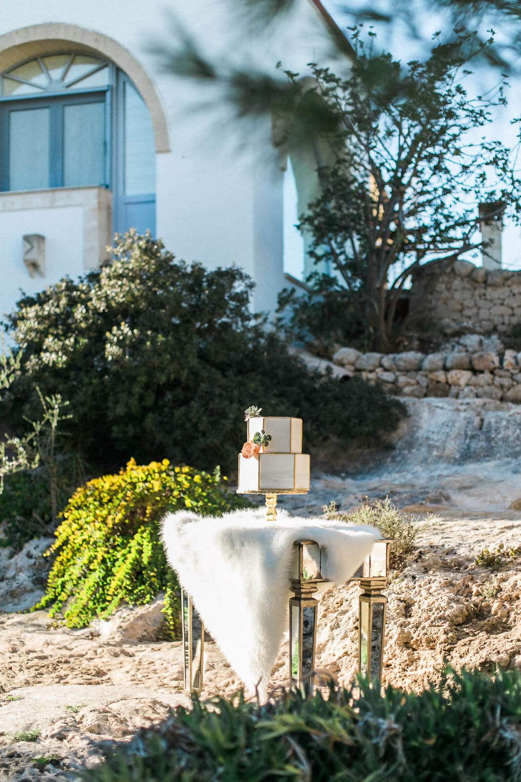 A wedding cake is sitting on a table in front of a white building.