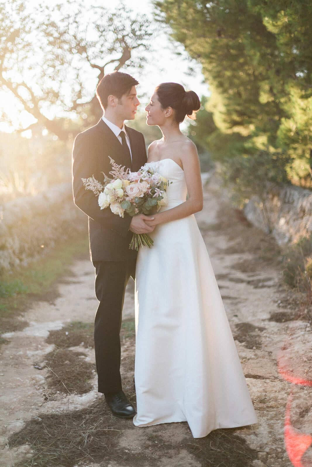 A bride and groom are standing next to each other and looking at each other.