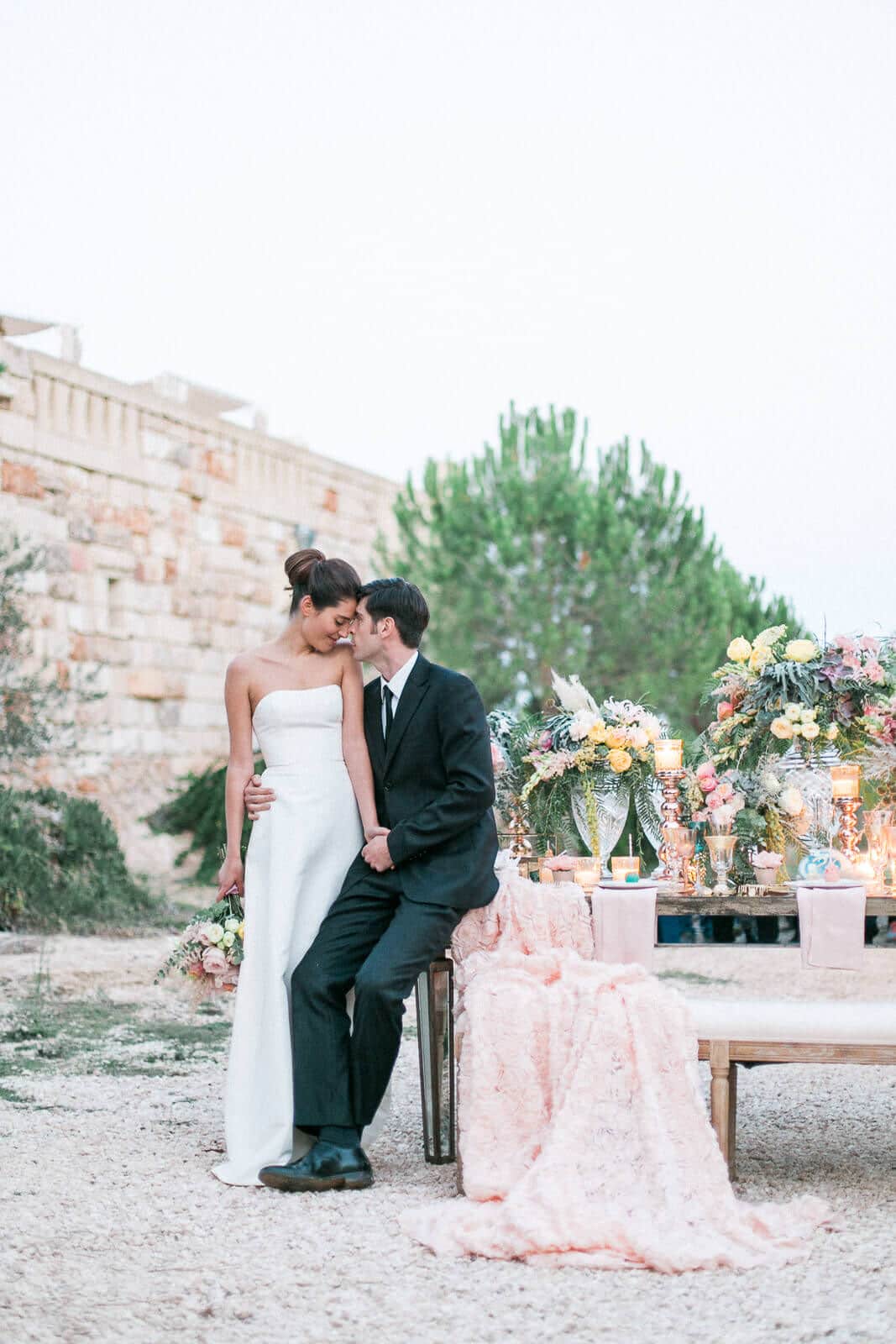 A bride and groom are sitting next to each other on a bench.