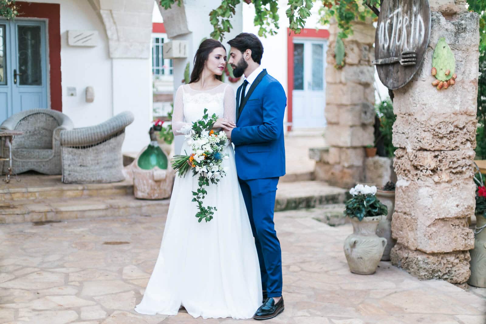 A bride and groom are posing for a picture in front of a building.