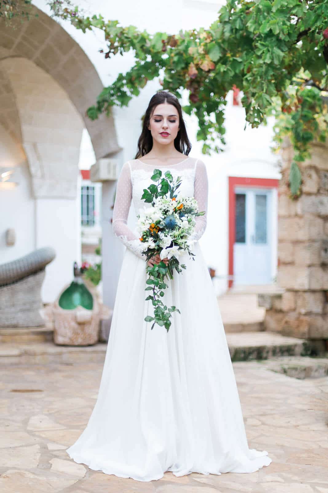 A bride in a white dress is holding a bouquet of flowers.