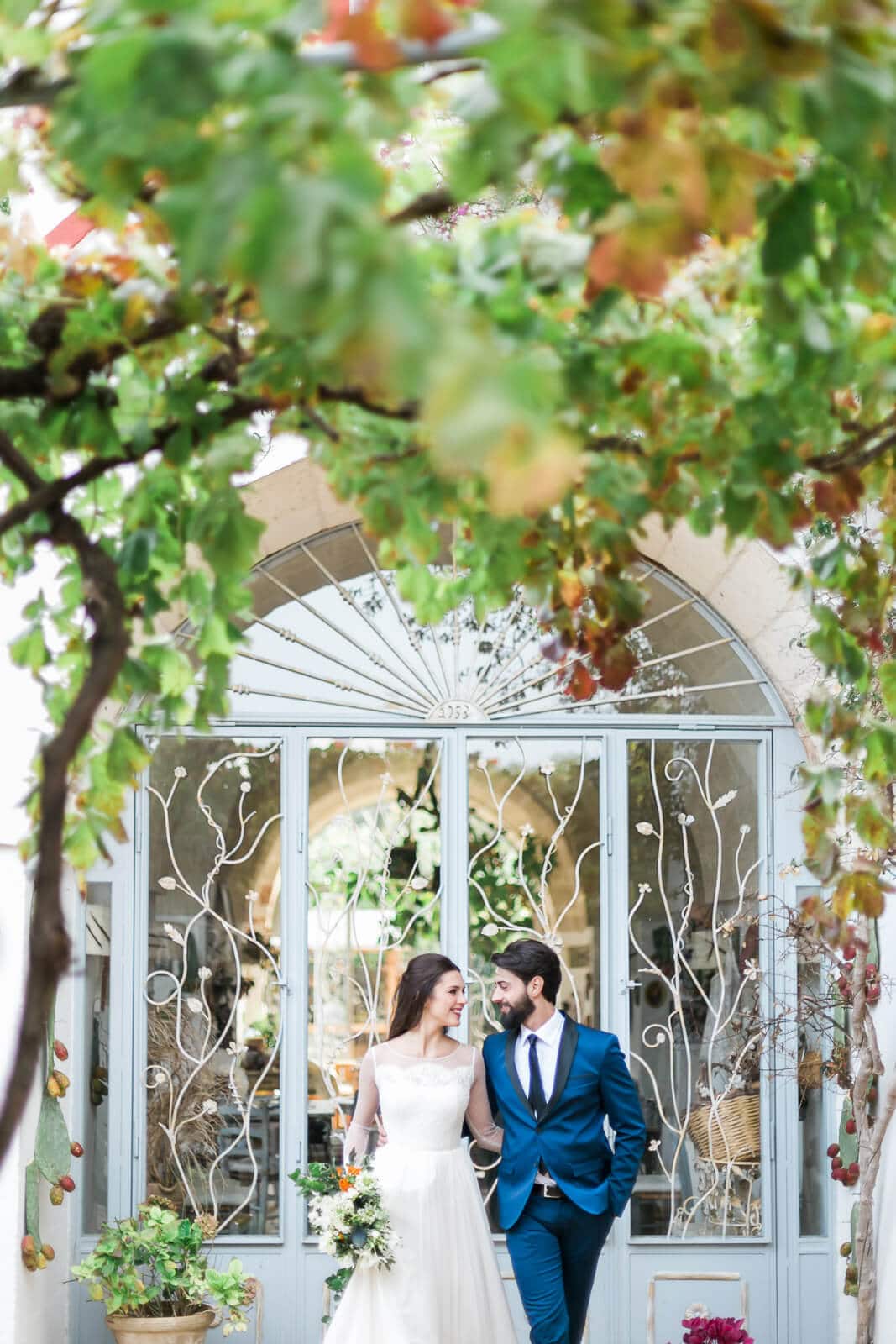 A bride and groom are walking in front of a building.