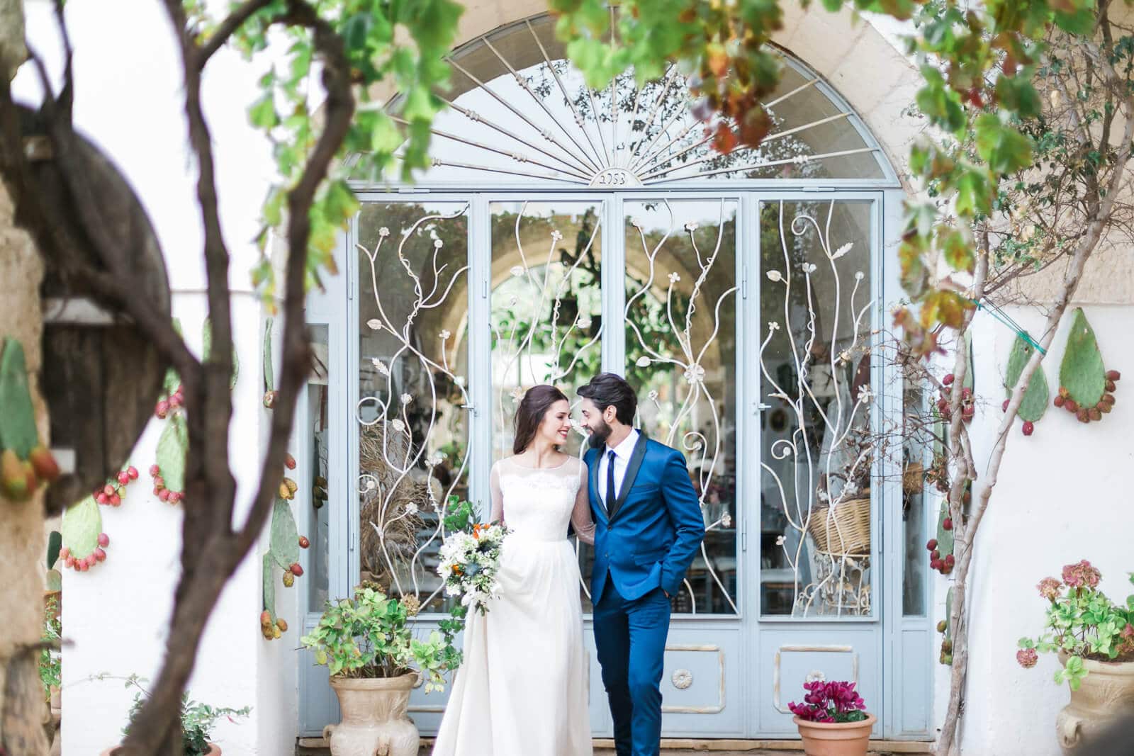 A bride and groom are kissing in front of a building.