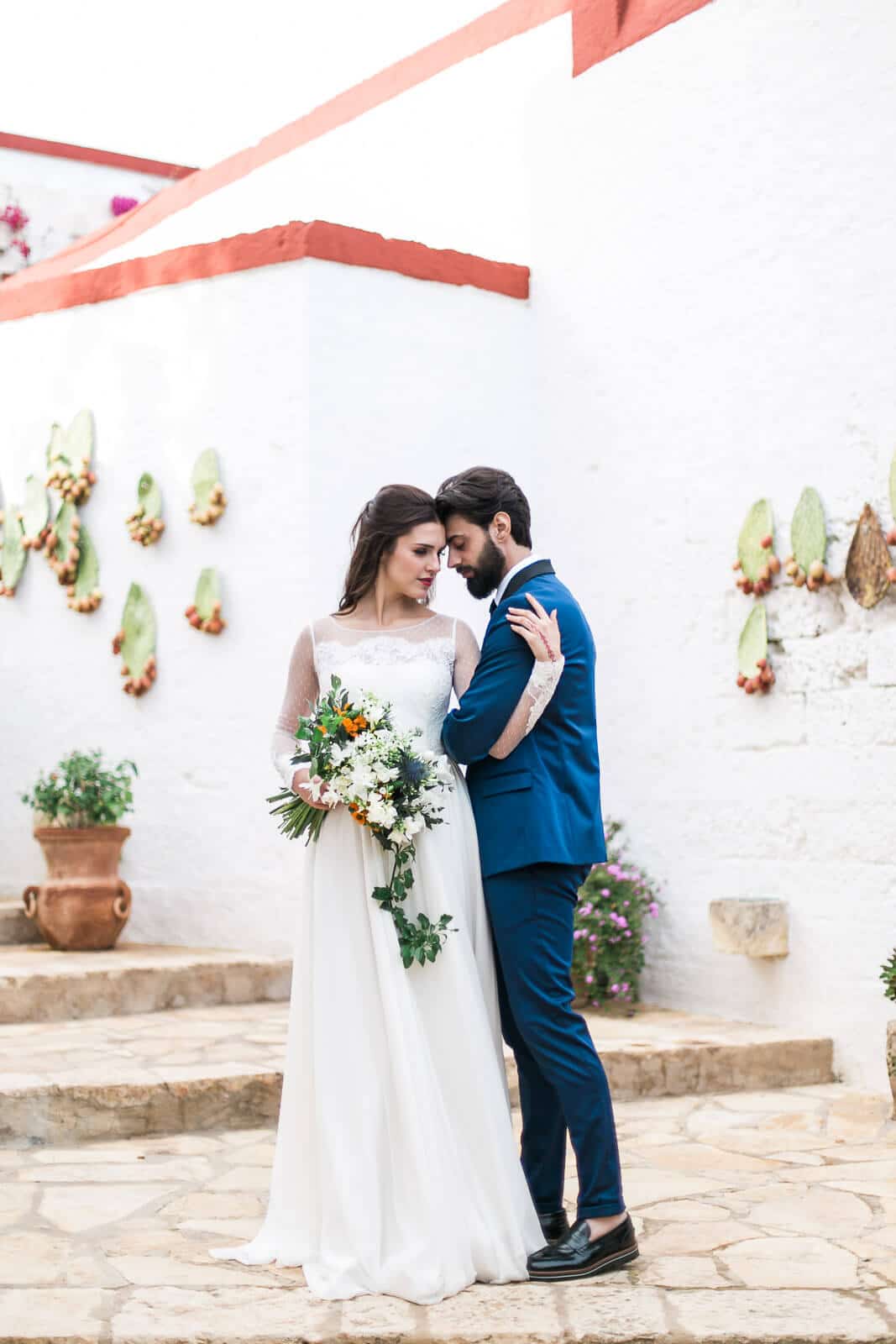A bride and groom are posing for a picture in front of a white building.