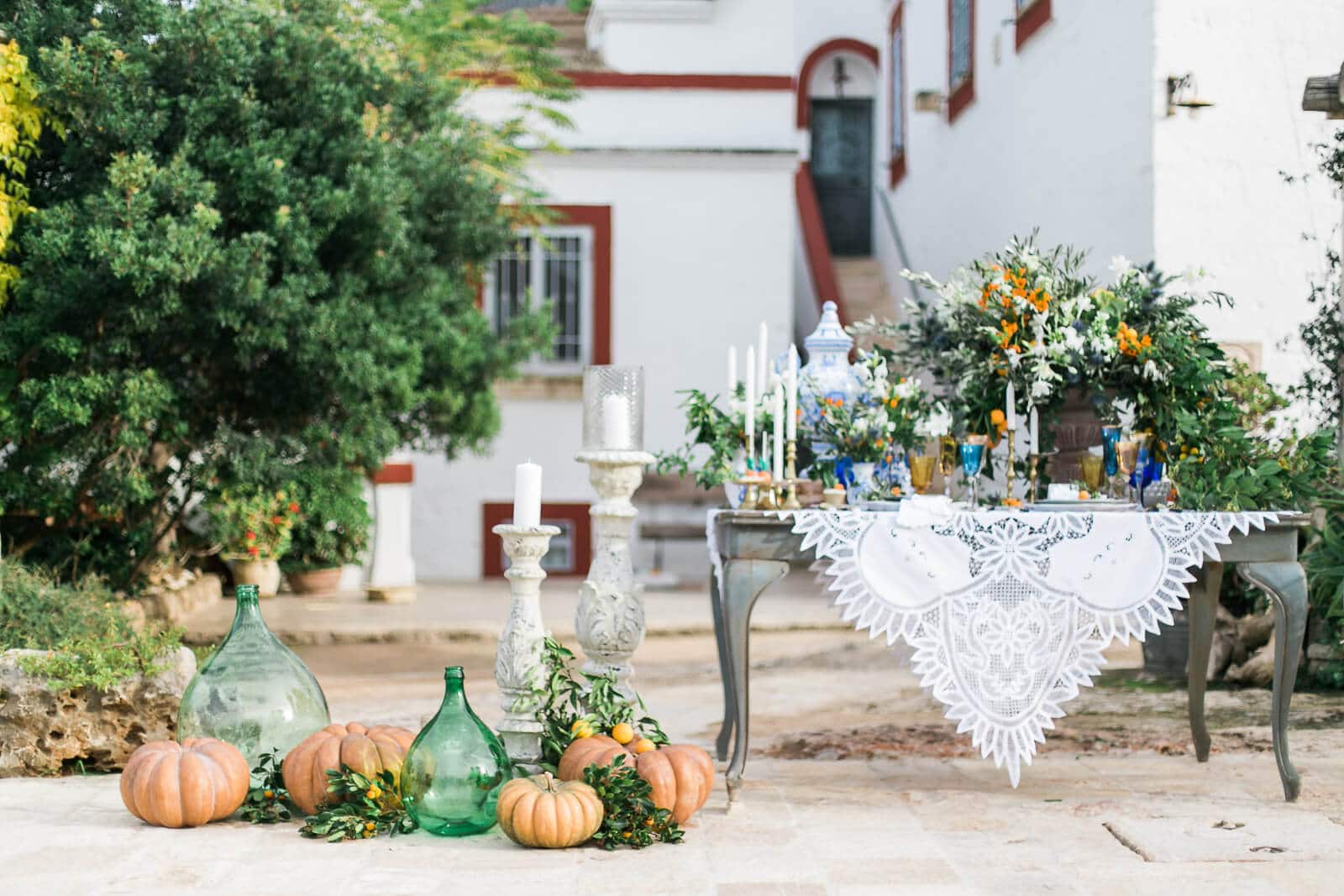 A table with pumpkins and candles on it in front of a house.