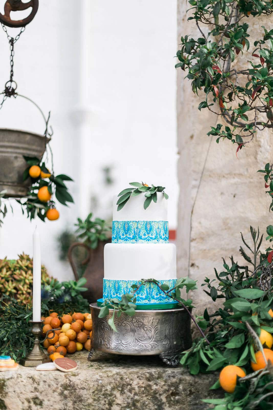 A wedding cake is sitting on a table in front of a tree with oranges.