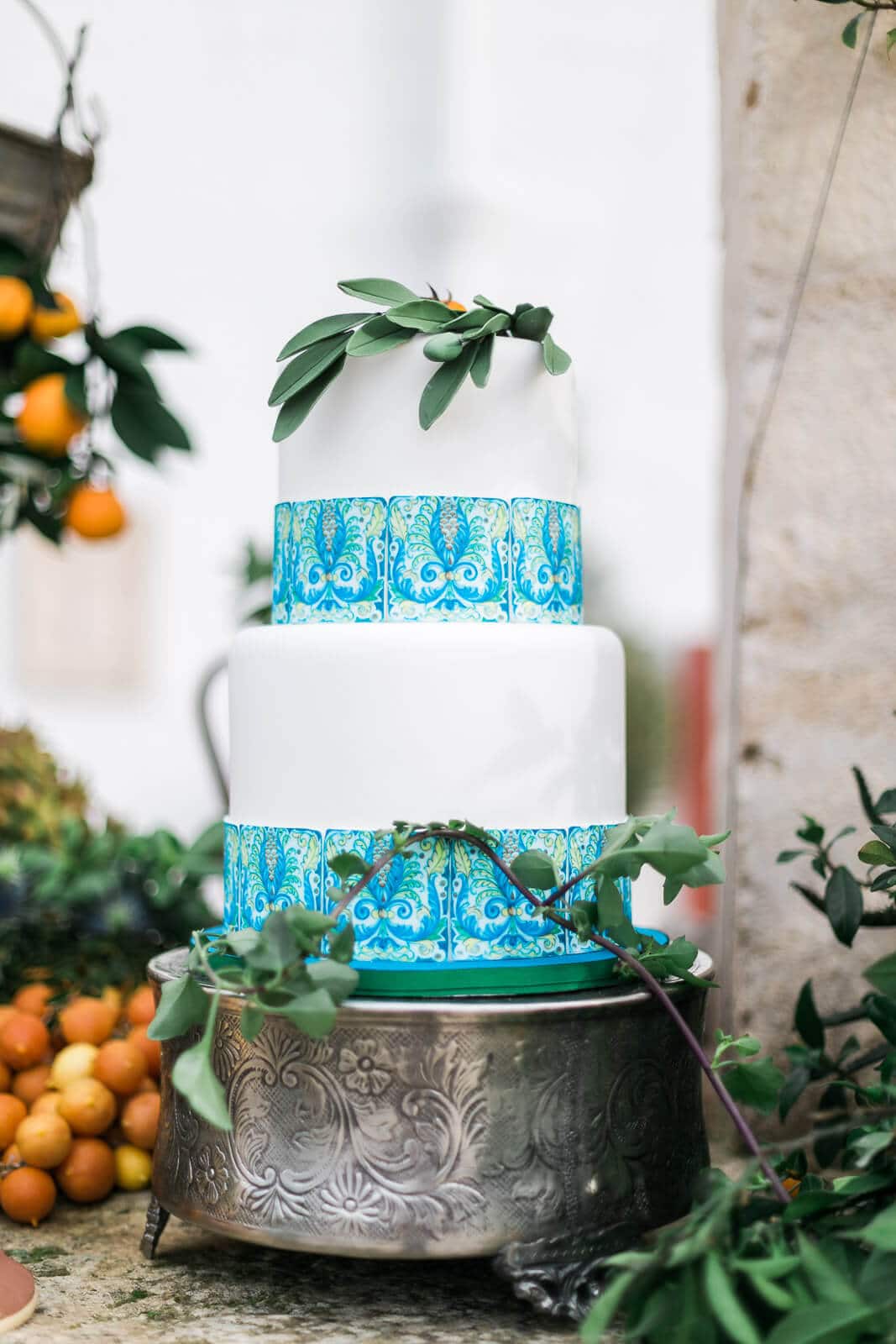 A blue and white wedding cake is sitting on top of a silver cake stand.