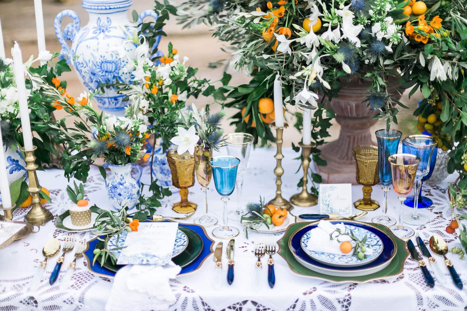 A table with plates , candles , vases and flowers on it.