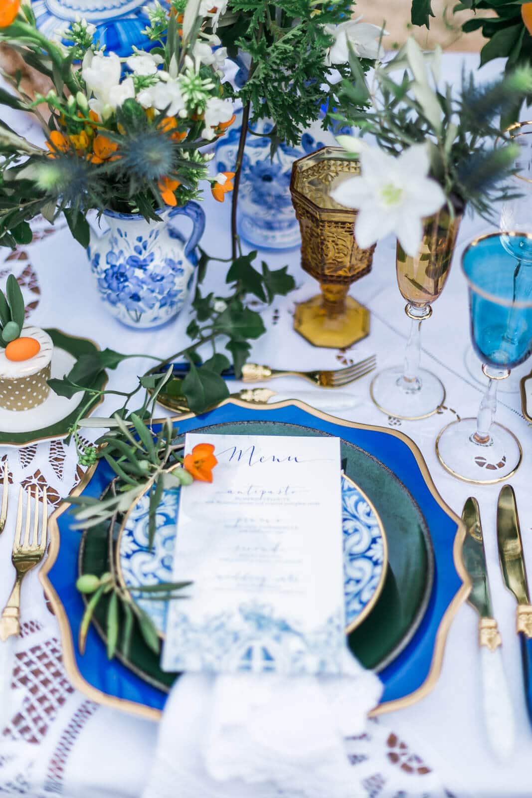 A table setting with blue and white plates , utensils , and flowers.