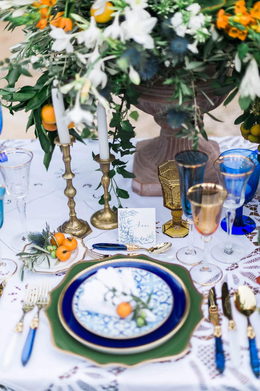A table with plates , candles , glasses and a vase of flowers on it.