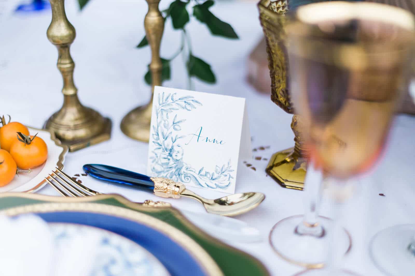 A table setting with plates , glasses , candles , and a place card.