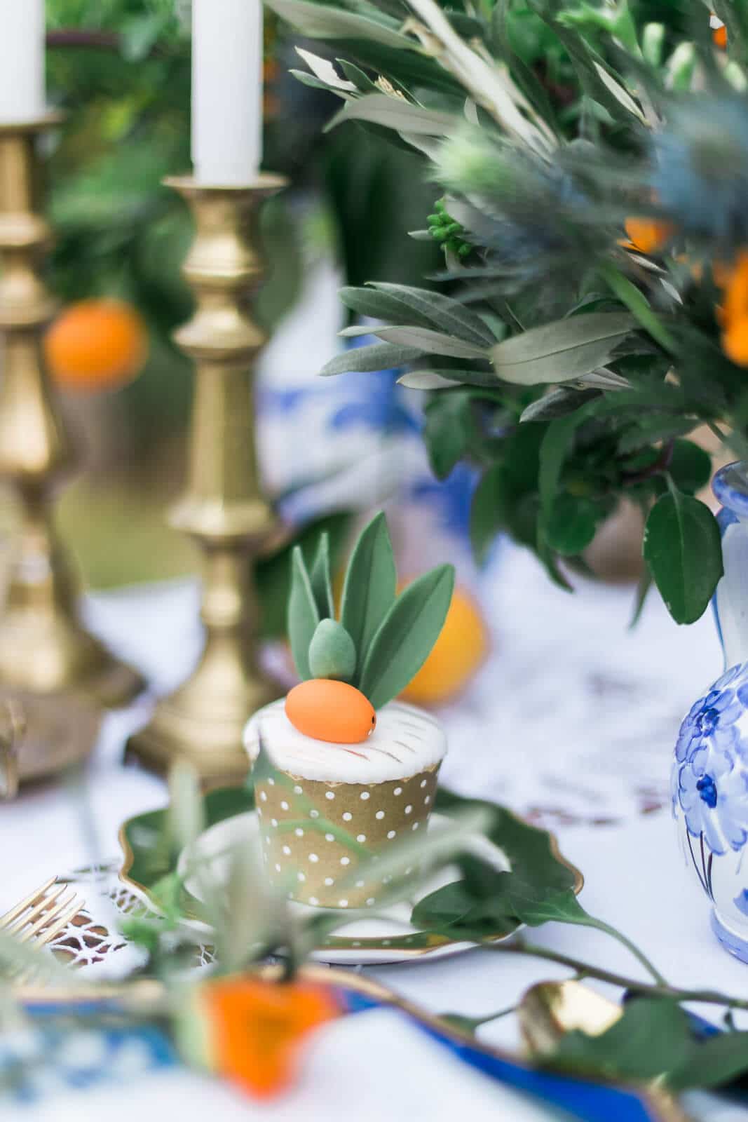 A cupcake with a carrot on top of it is sitting on a plate on a table.