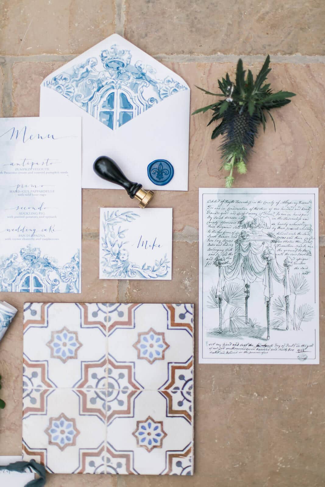 A wedding invitation and envelope are sitting on a tiled floor.