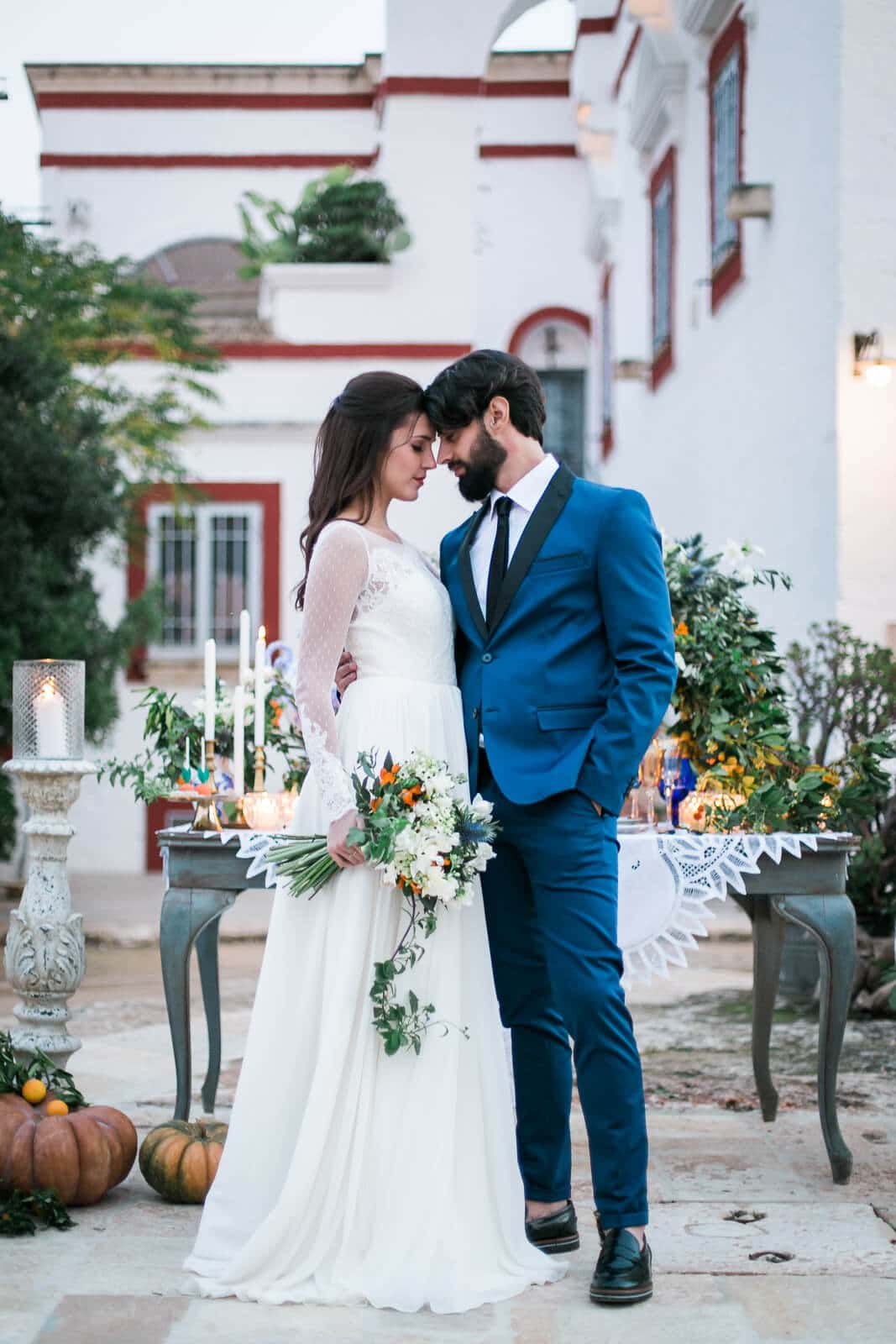 A bride and groom are standing next to each other in front of a white building.