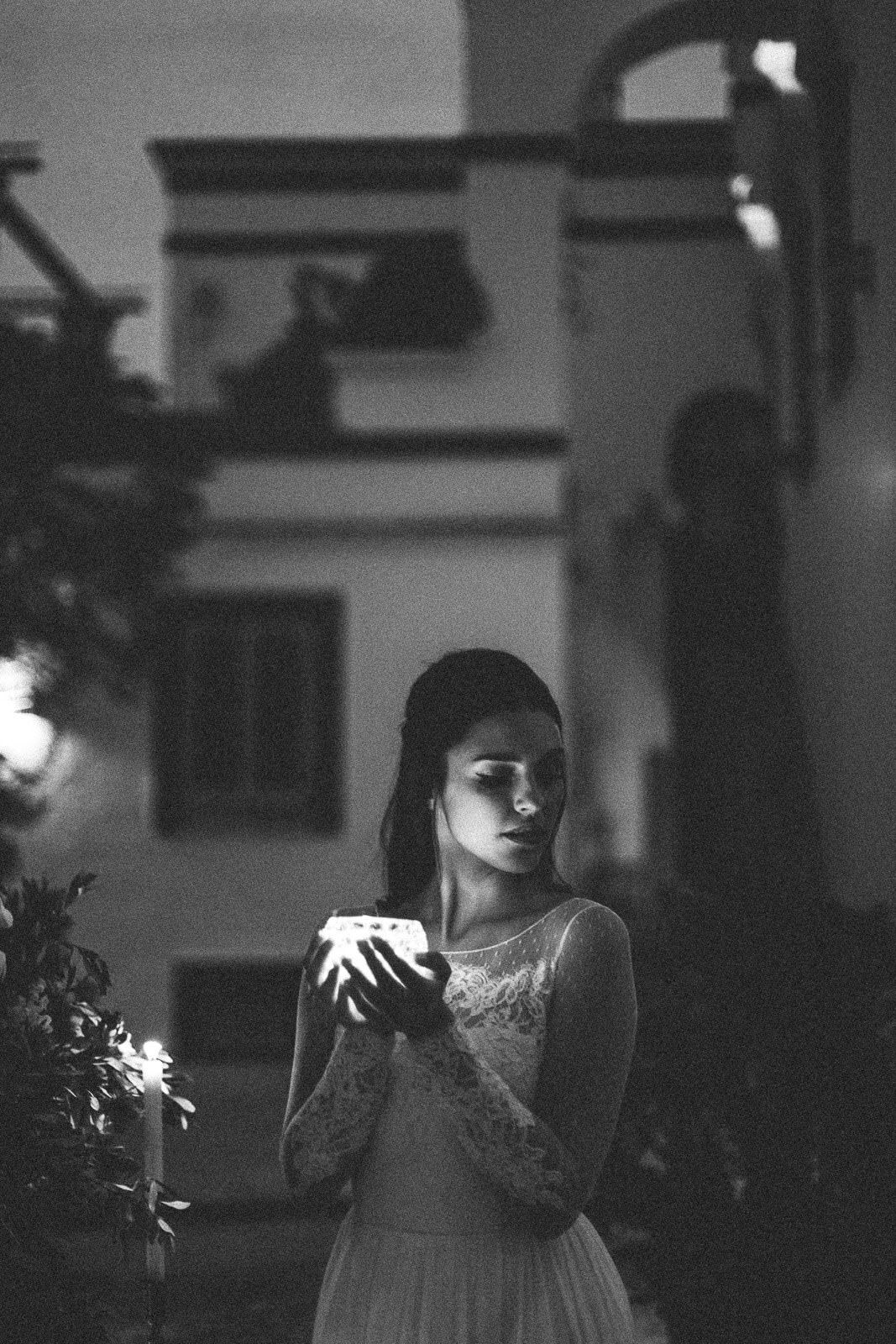 A black and white photo of a woman in a wedding dress holding a candle.