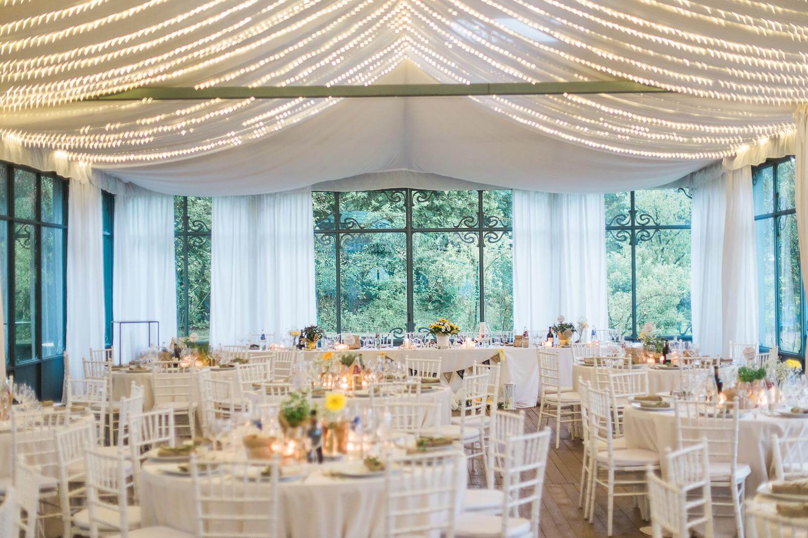 A large room with tables and chairs set up for a wedding reception.