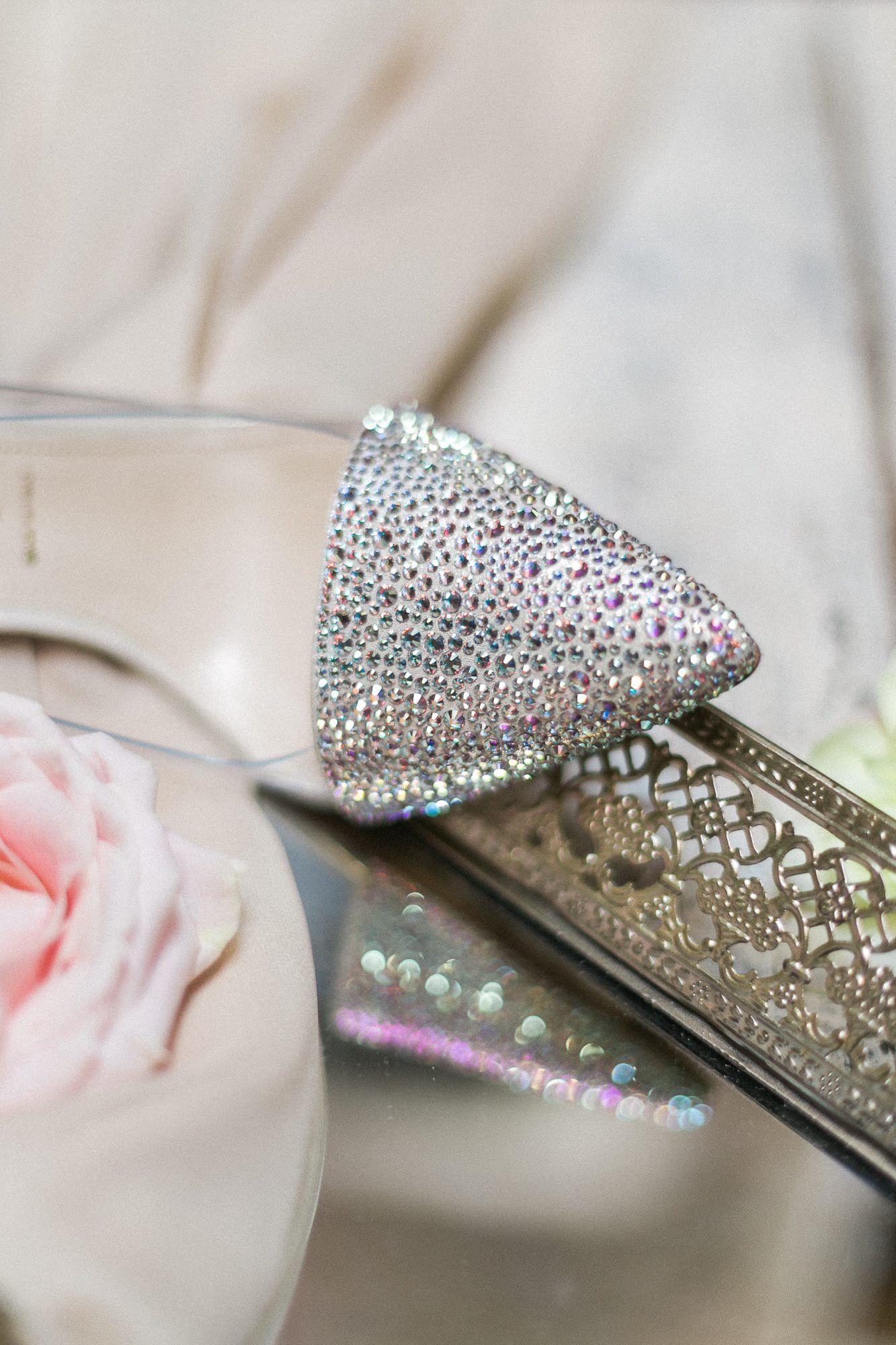 A pair of shoes with rhinestones on them are sitting on a table next to a rose.