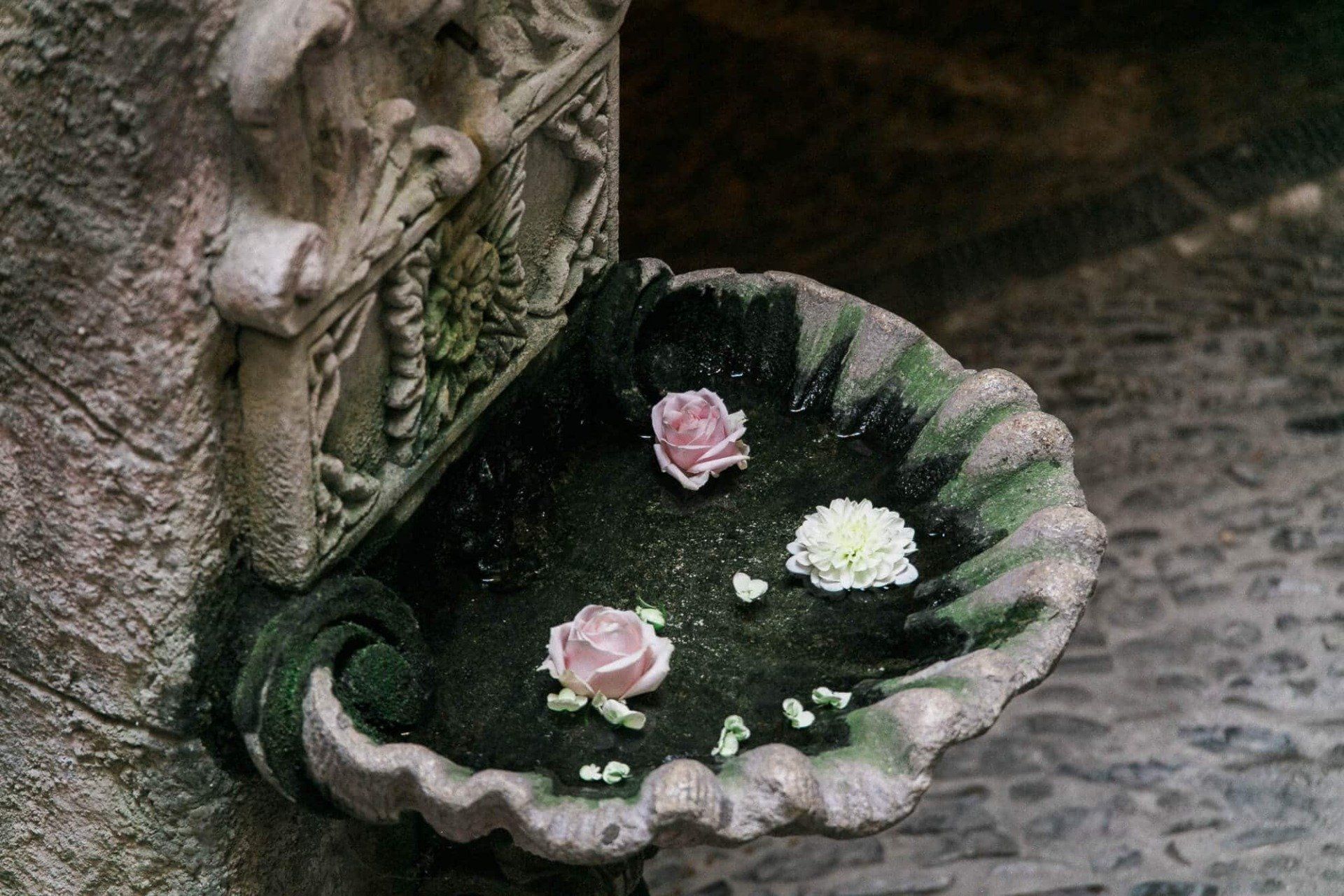 A stone bowl with pink and white flowers in it