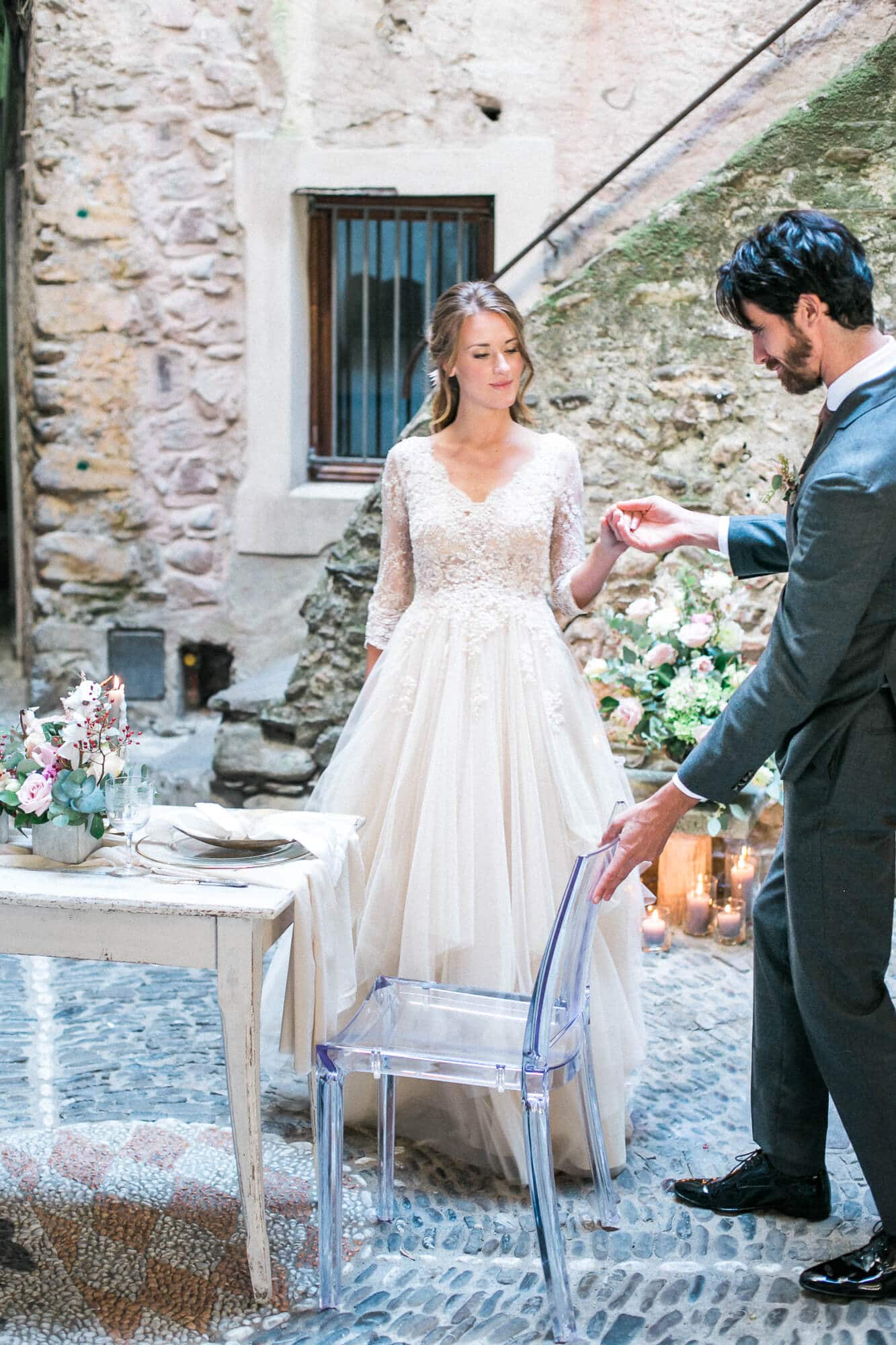 A bride and groom are standing next to each other in front of a table.