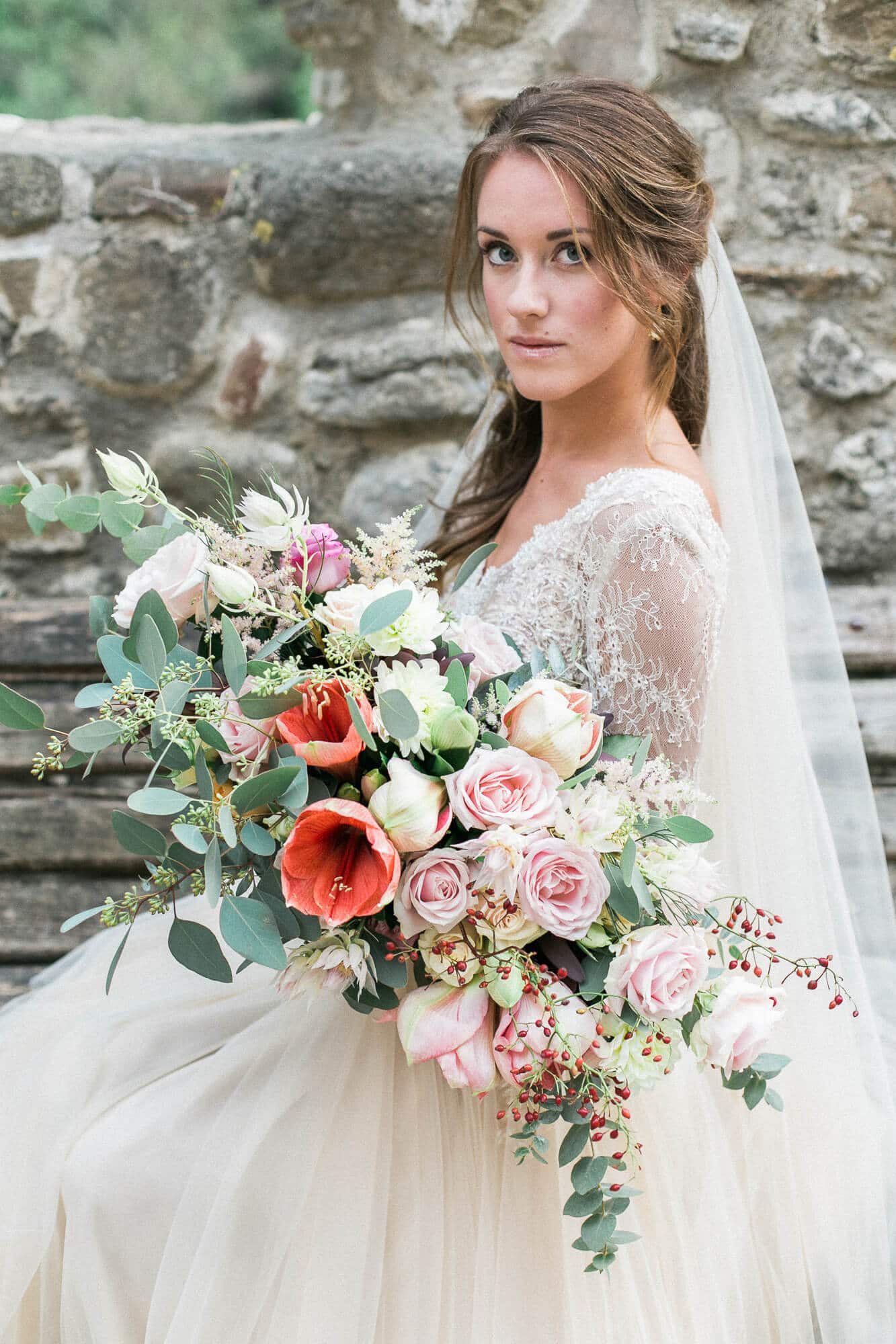 A bride in a wedding dress is holding a large bouquet of flowers.