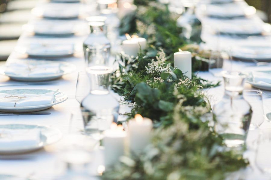 A long table with plates , glasses , and candles on it.