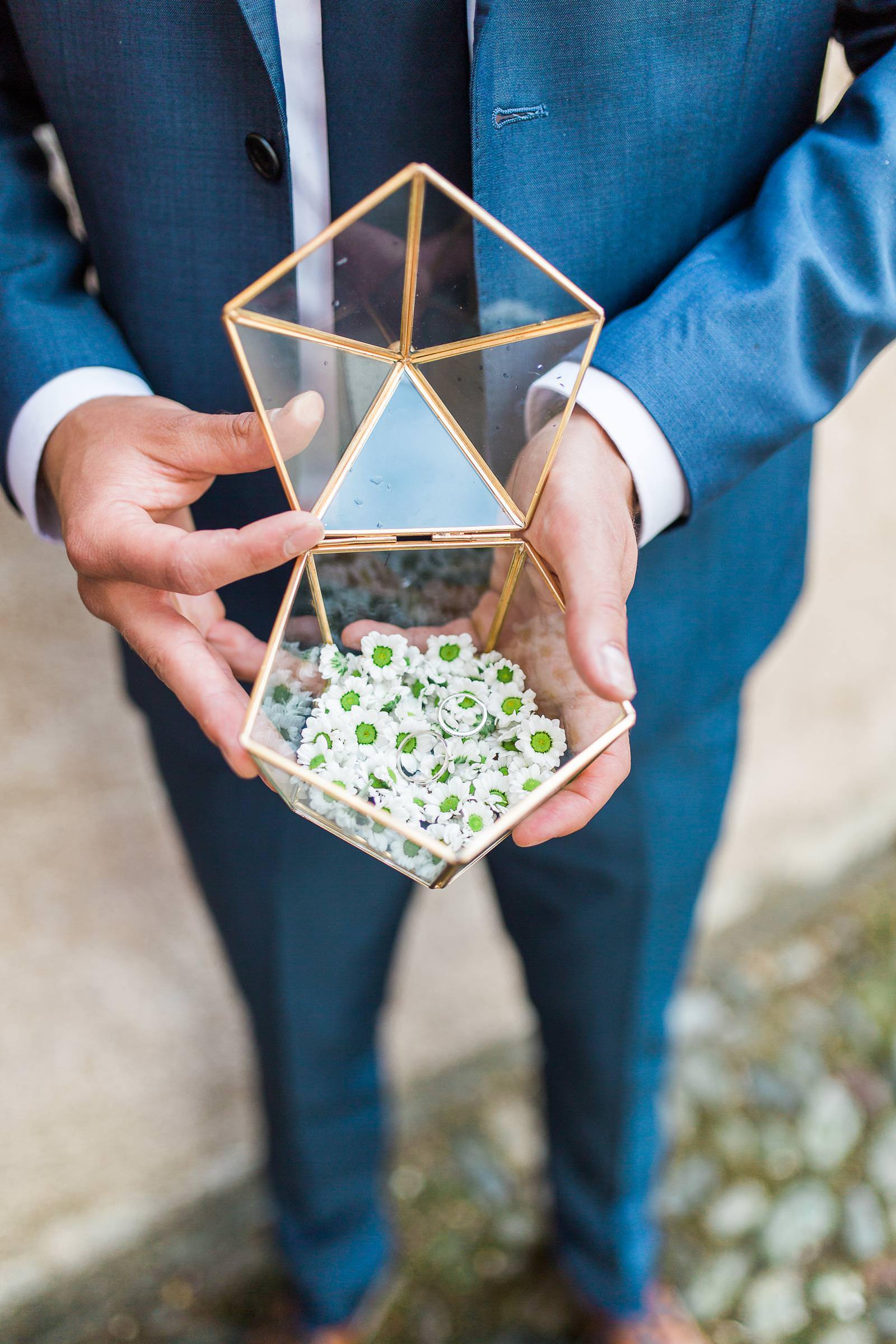 A man in a suit is holding a glass box with flowers in it.