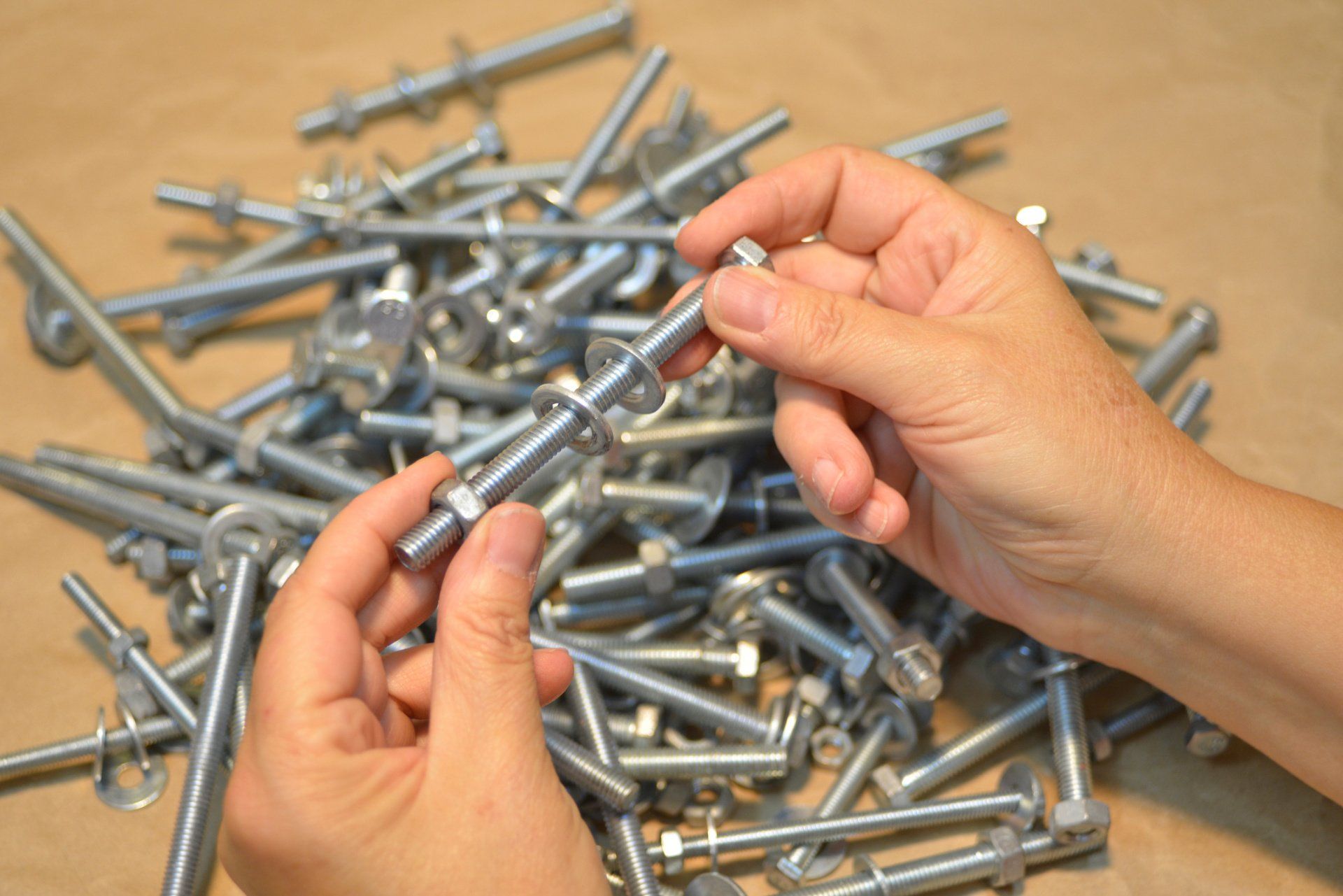 Man Inserting Washer And Nuts On A Bolt — Springfield, MI — Schweitzer Bros. Inc