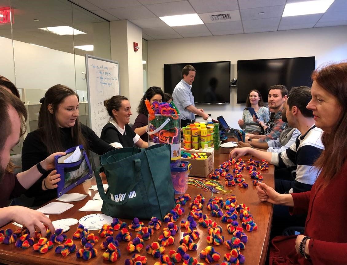 Image of Stax Boston employees assembling fine motor kits in a conference room.