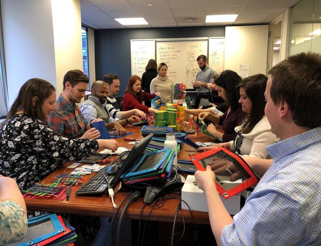 Image of Stax Boston employees assembling fine motor kits in a conference room.