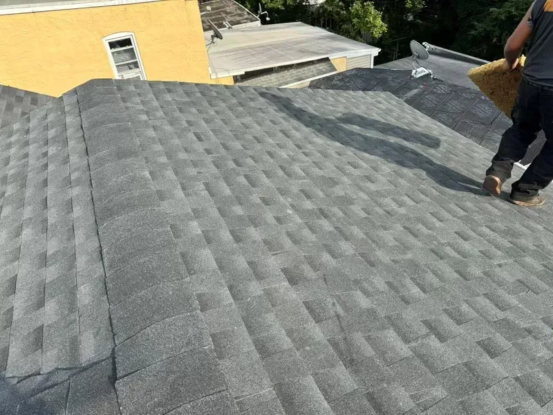 A man is standing on top of a roof with a broom.