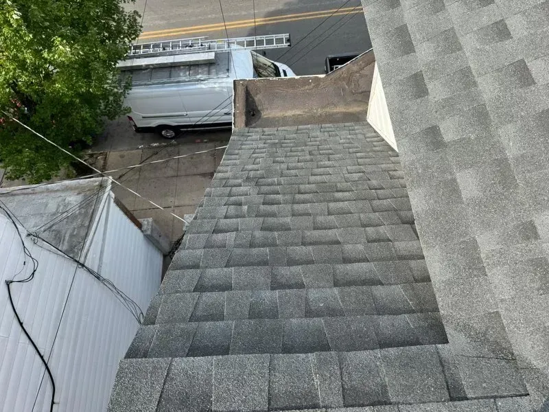 A white van is parked on the side of a building next to a roof.