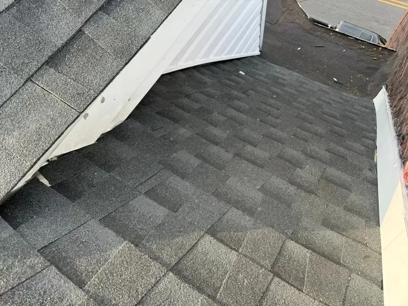 A close up of a roof with a white wall behind it.