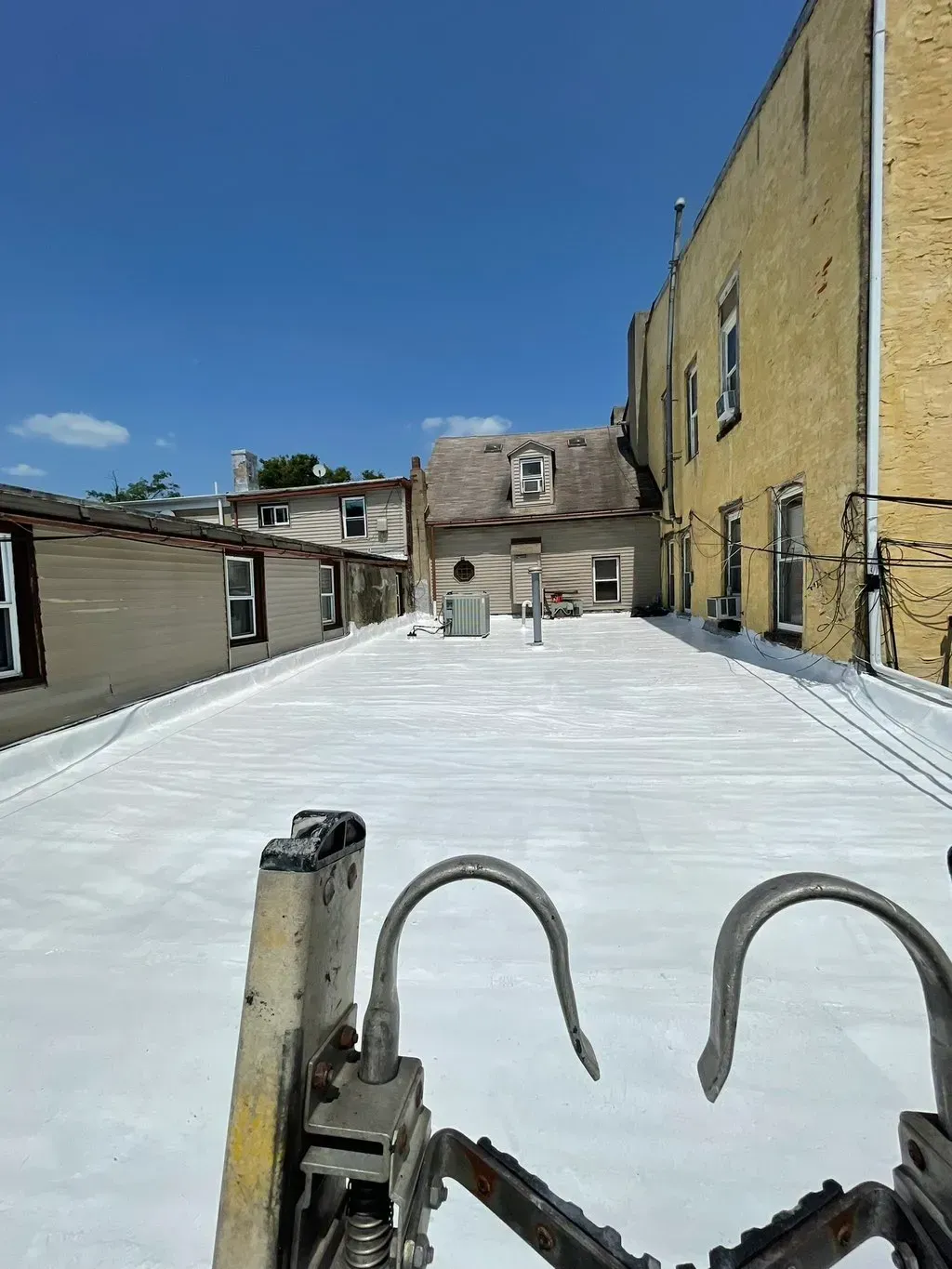A ladder is sitting on top of a white roof next to a building.