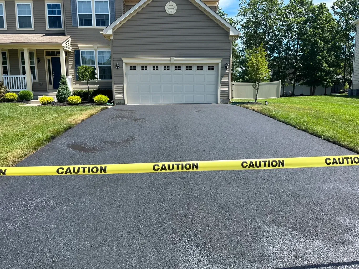 A driveway with a yellow tape that says caution on it