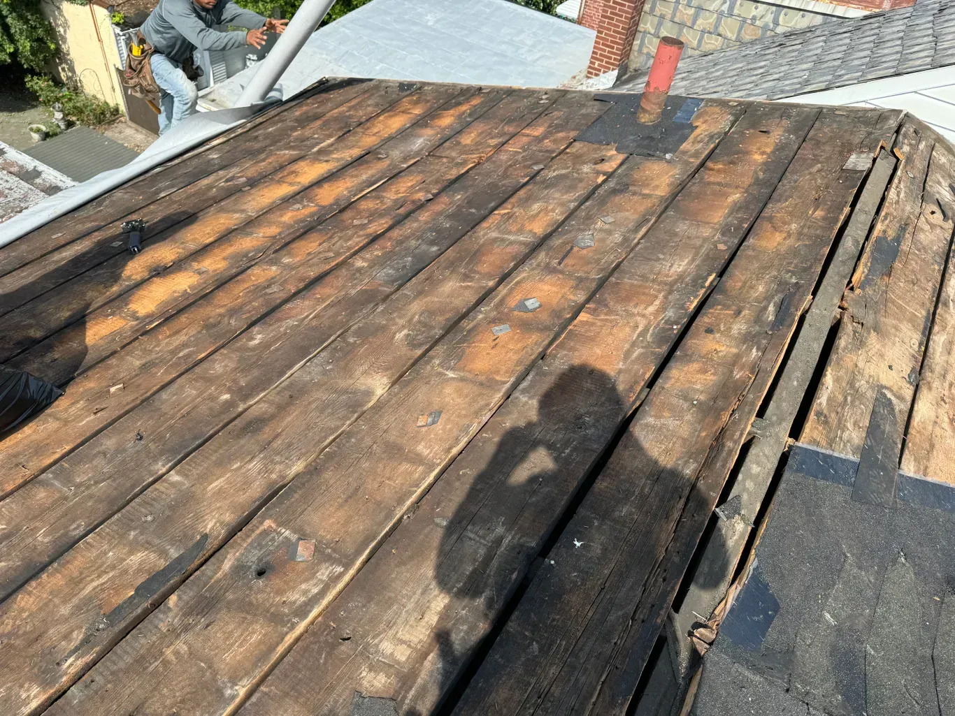 A man is sitting on top of a wooden roof.