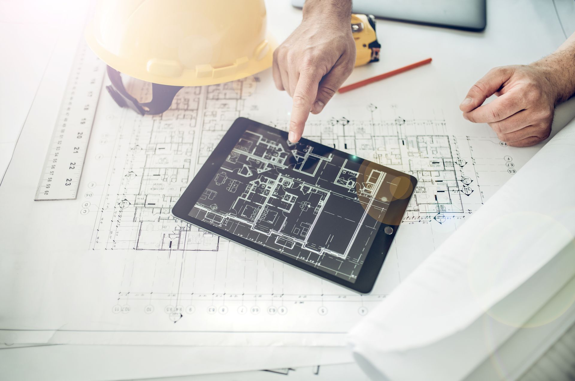 A man is pointing at a tablet with a blueprint on it.