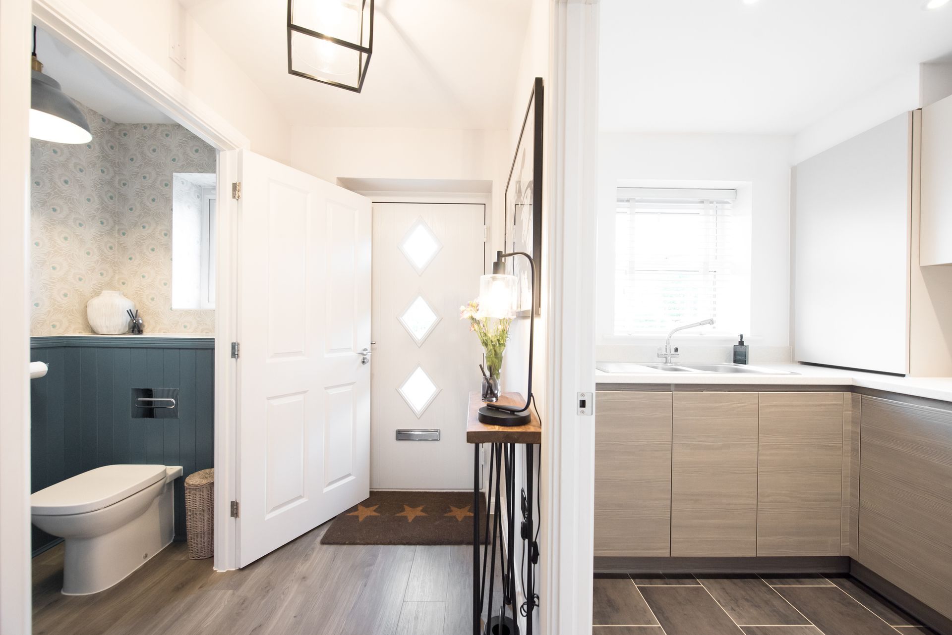 A hallway leading to a bathroom and a kitchen in a house.