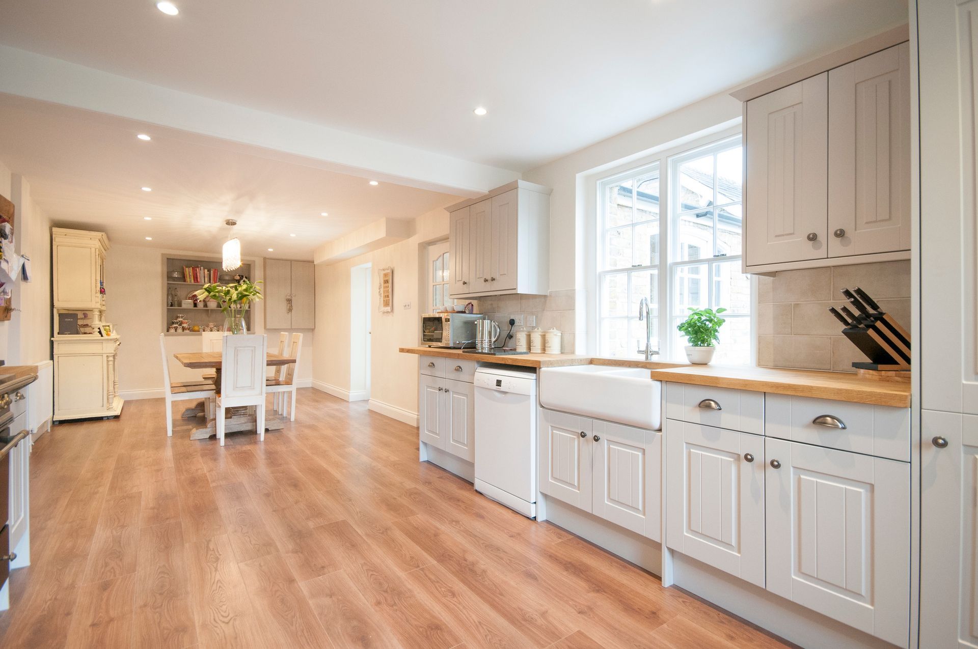 A kitchen with white cabinets and wooden floors and a sink.