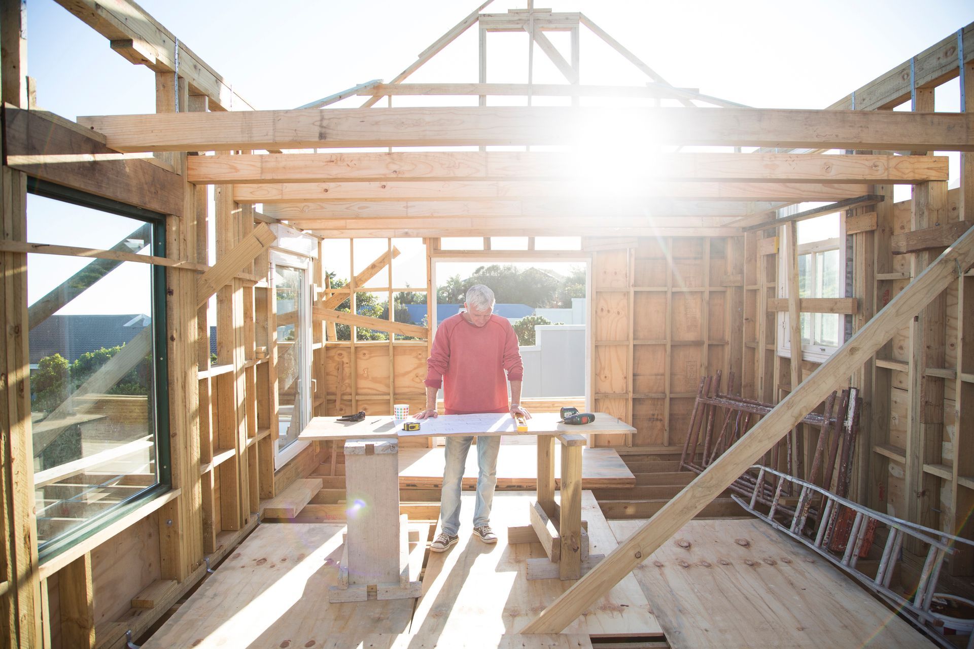 A man is standing in the middle of a wooden house under construction.
