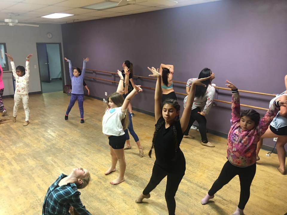 A group of young girls are dancing in a dance studio.