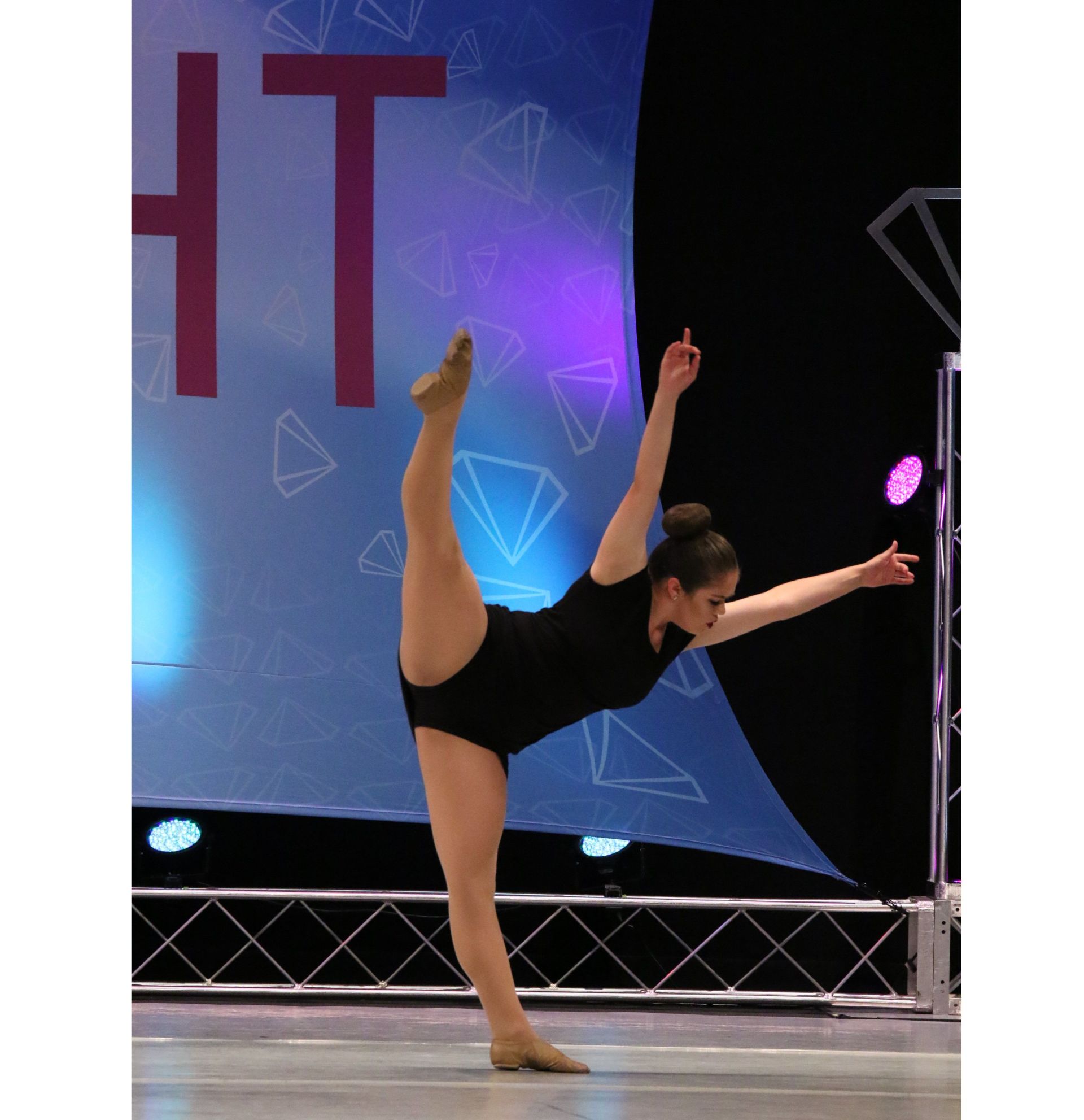 A woman is doing a split in front of a sign that says ht