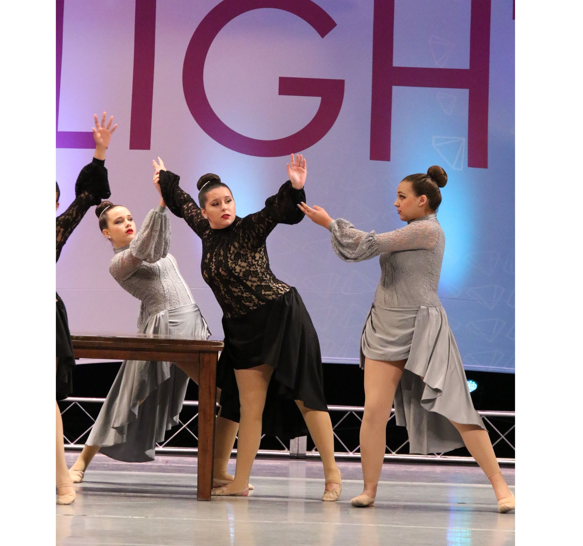 Three women are dancing in front of a sign that says high