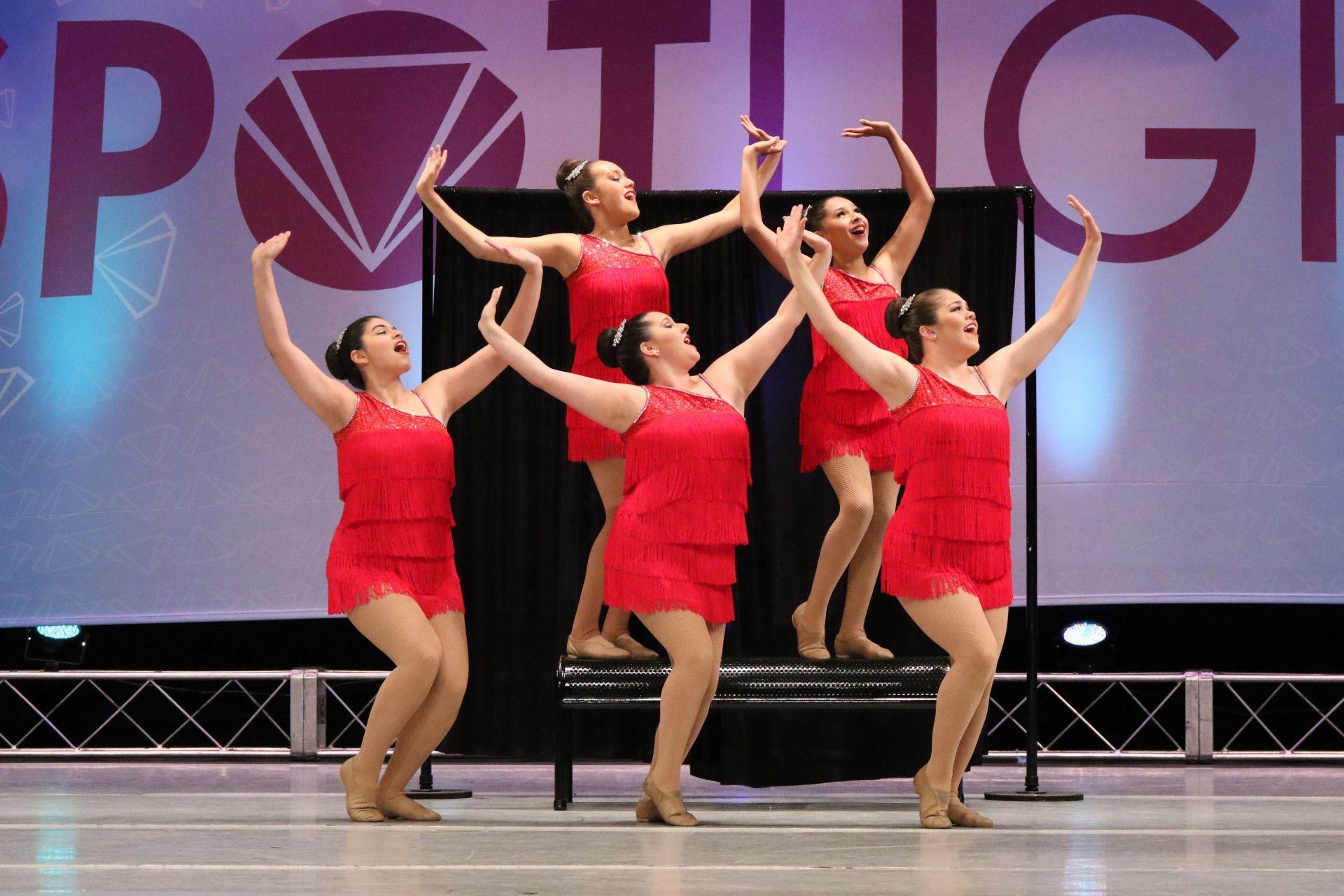 A group of women in red dresses are dancing on a stage.